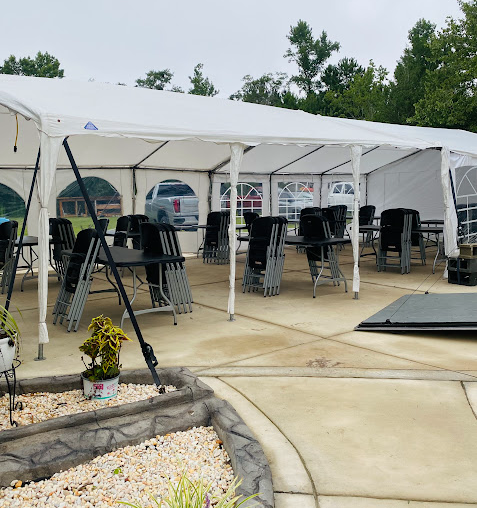 Party tent with rows of black chairs and tables on a patio