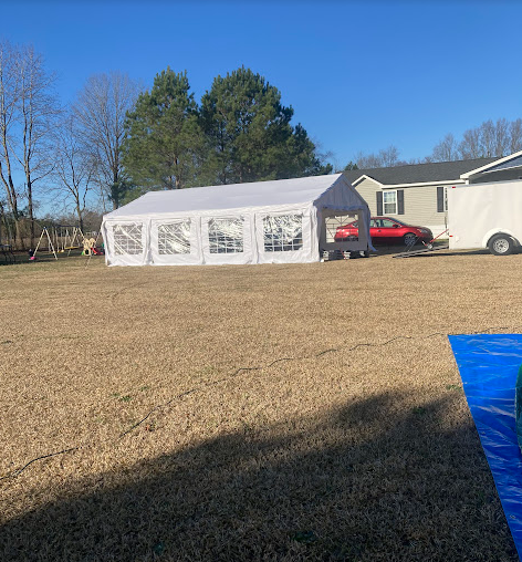 Large white party tent set up in an open yard